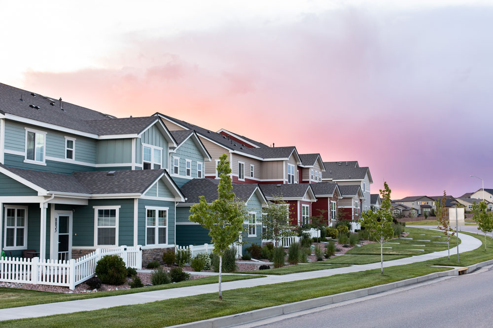 Multi-colored two-story homes in neat rows with white picket fences