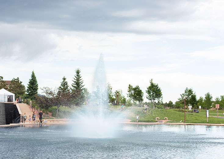 A clear blue pool with a fountain jet shooting water upwards in the center