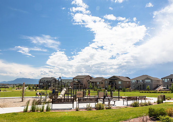 Apartment buildings with mountain backdrop overlooking a playscape area