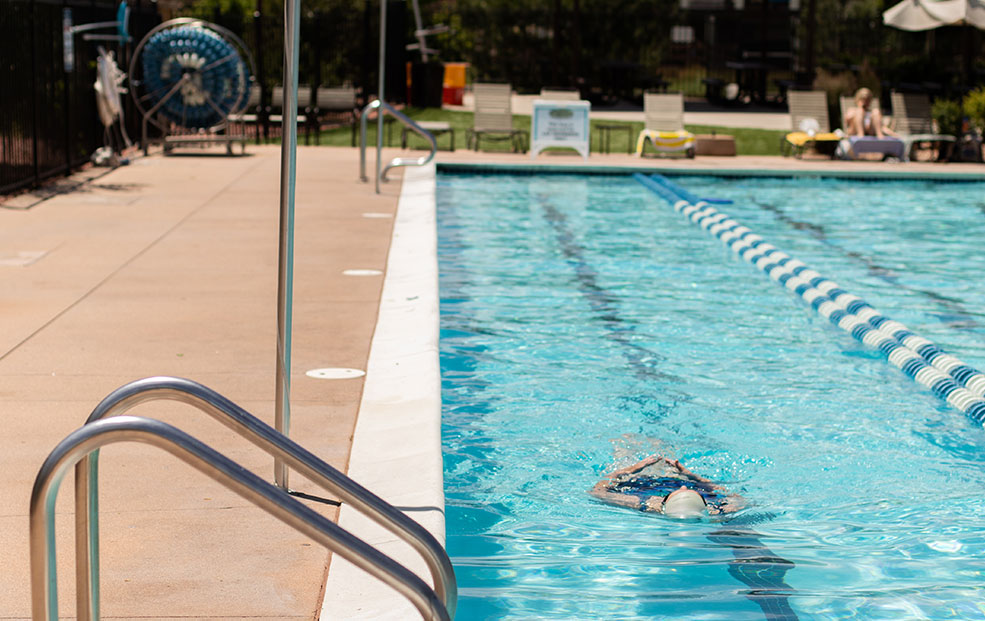 a person swimming in a sparkling blue swimming pool on a sunny day