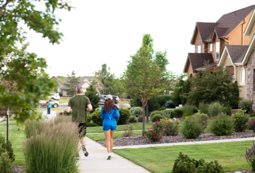 A man and woman jog together in a neighborhood