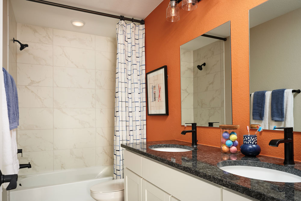 A guest bathroom with a dark granite countertop and tiled shower