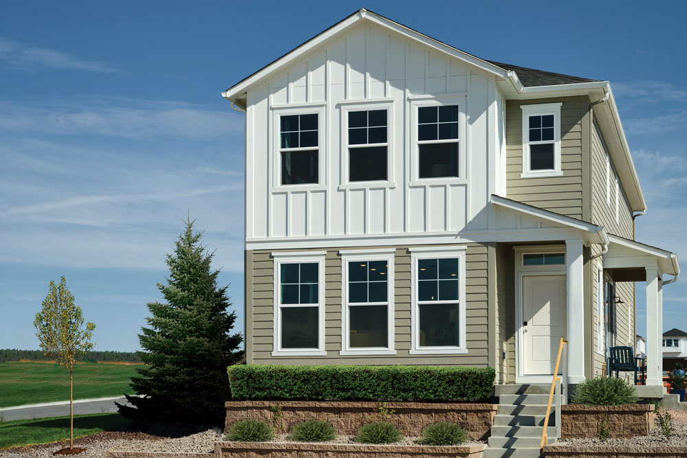 A 2-story white and beige townhouse with manicured green hedges